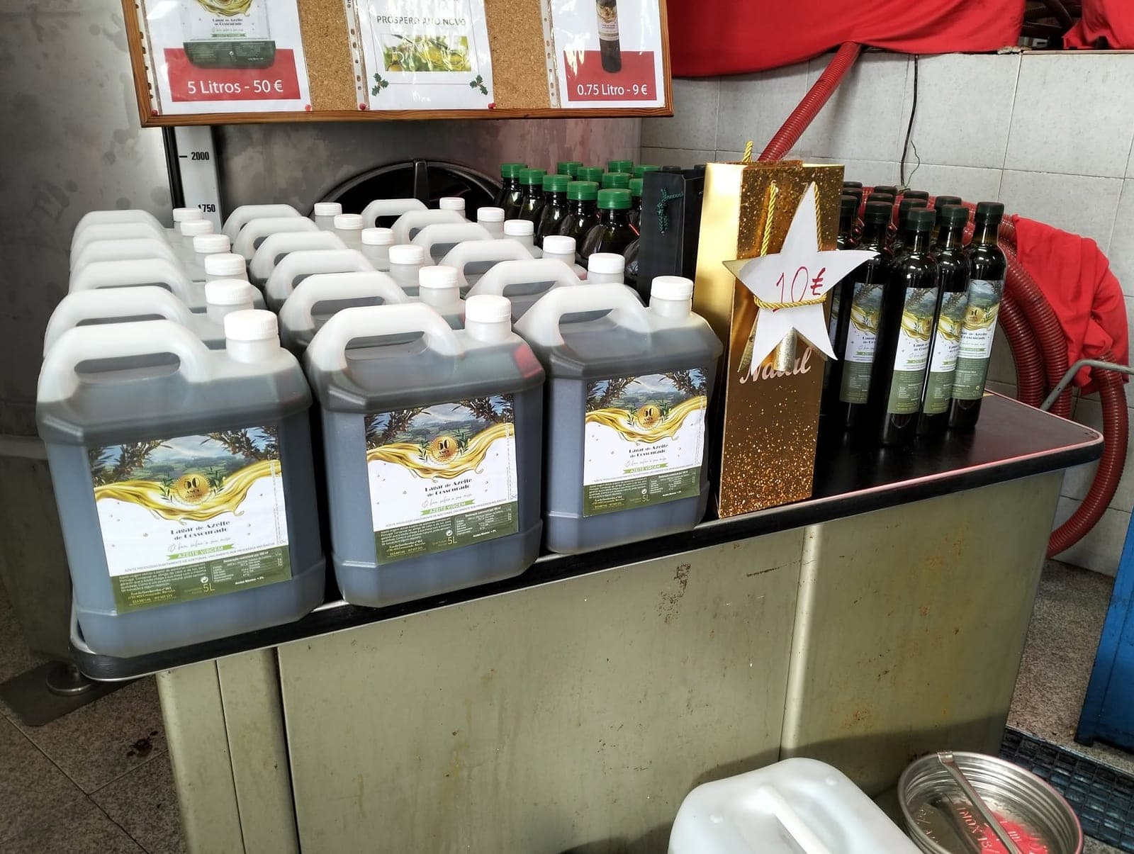 Garrafões de 5 L e garrafas de 0,75 L à venda no lagar, ao lado de um saco de Natal